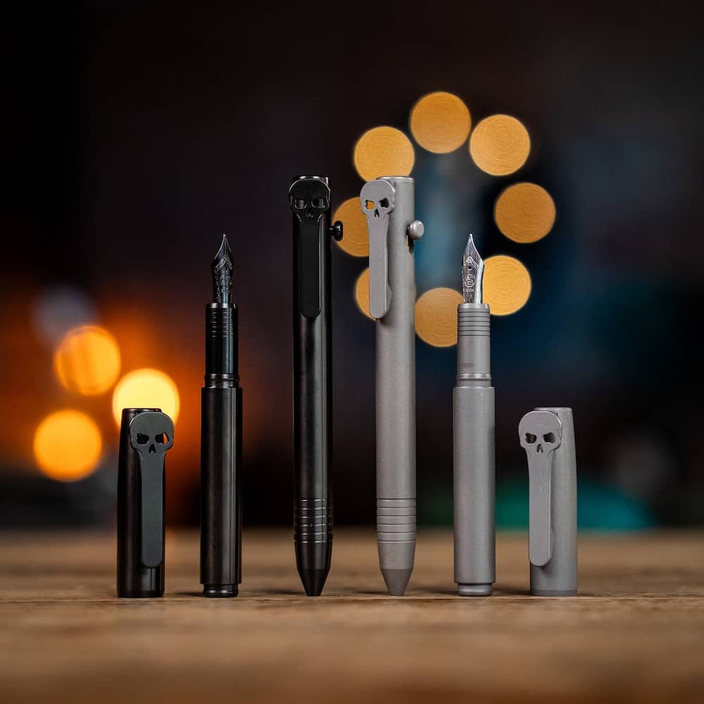 Chaves pens in black and gray with skull designs, displayed at various angles on a wooden surface