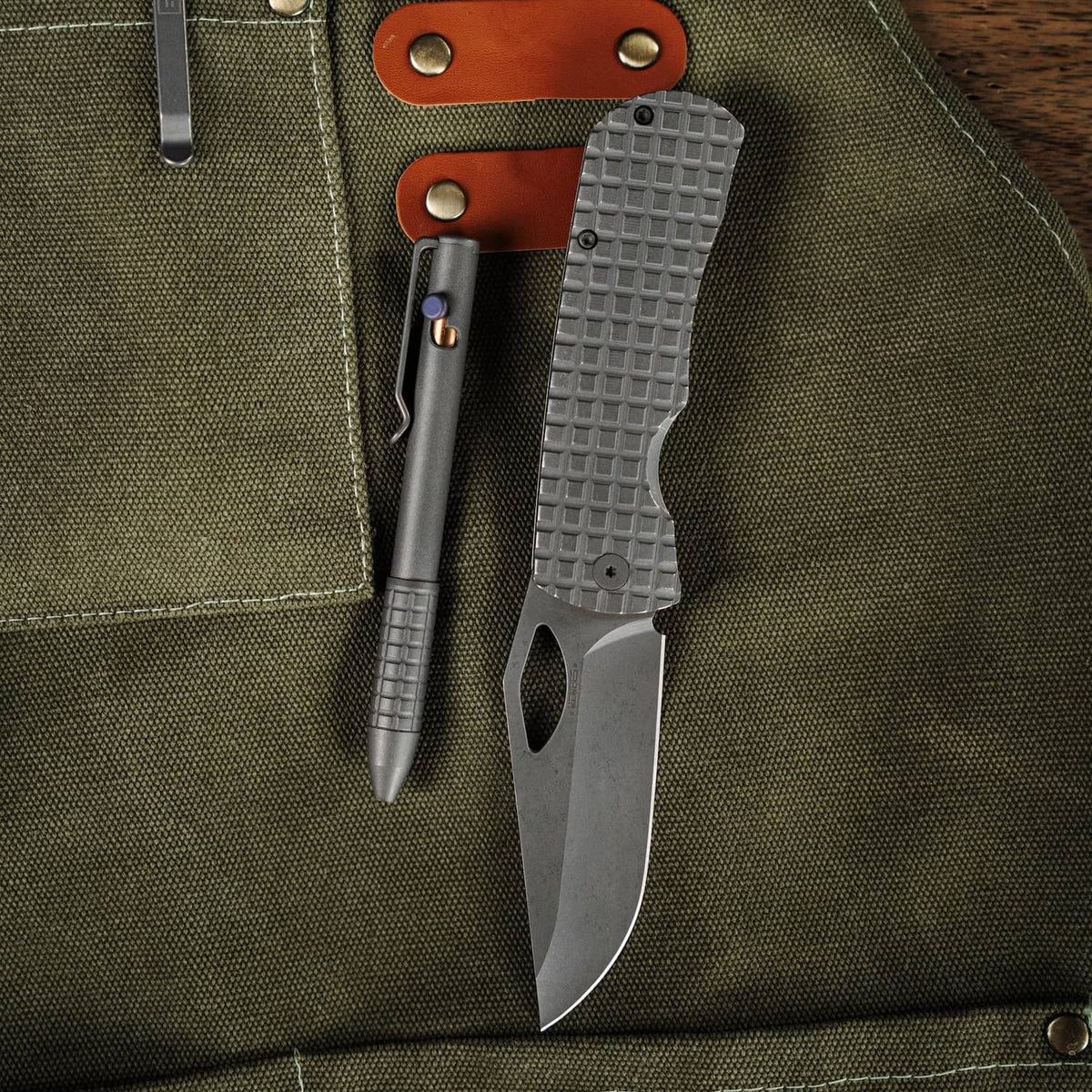 McNeese Pen in grey finish with textured grip placed on a green canvas apron