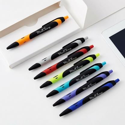 Eight colorful Xpress Blackmore retractable pens by PensXpress, each with a black grip, are lined up on a white surface beside a white box and the edge of a tablet.