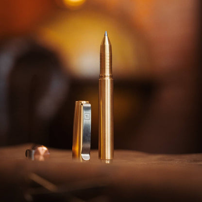 Titanium capped pen with sleek metallic gold body and silver clip on wooden surface