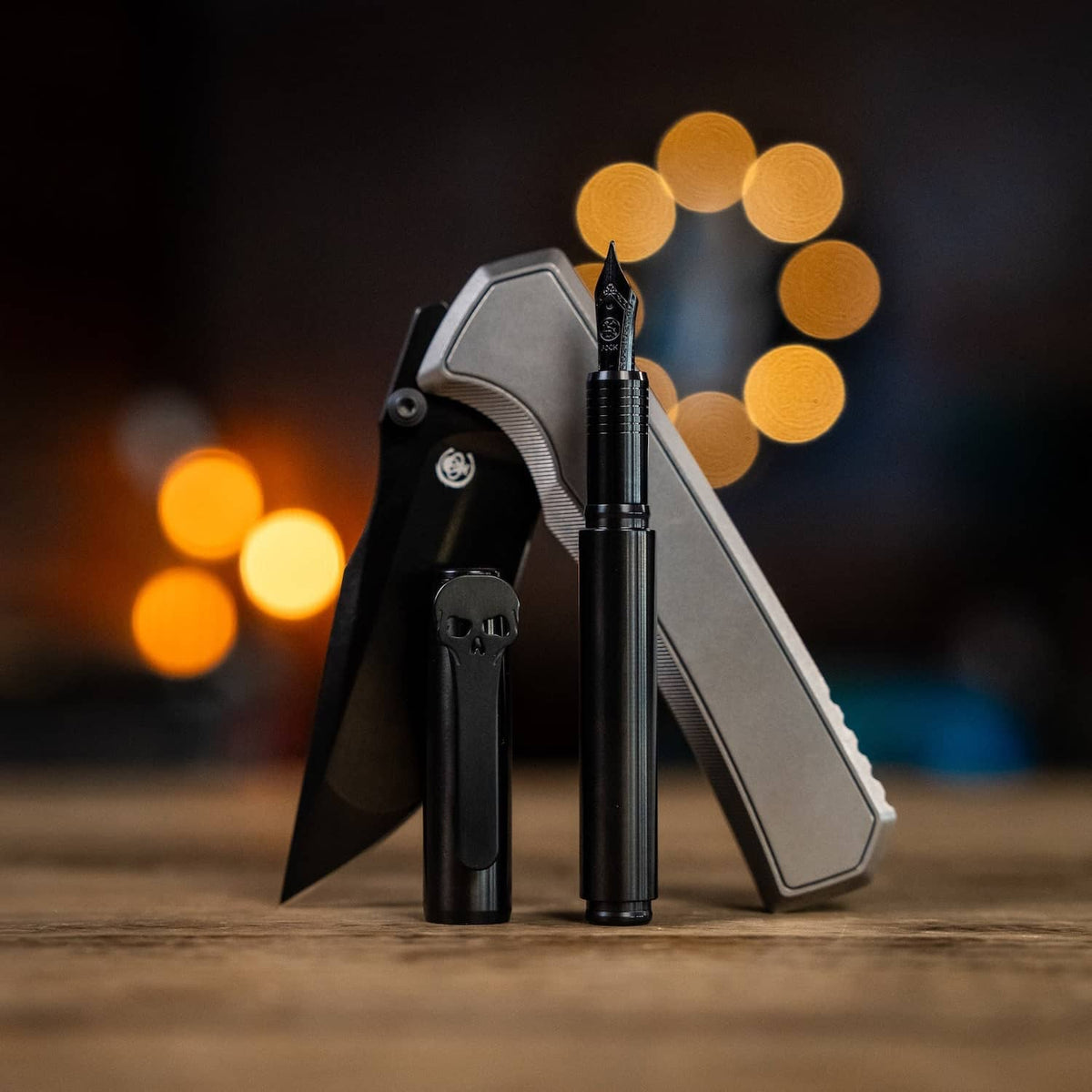 Chaves pens in black finish beside a stylish gray folding knife on a wooden surface