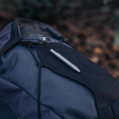 EDC titanium mini pen from Big Idea Design LLC clipped to black and gray backpack outdoors