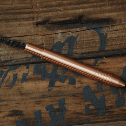 Big Idea Design LLC EDC titanium mini pen in copper finish with attached lanyard on wooden background