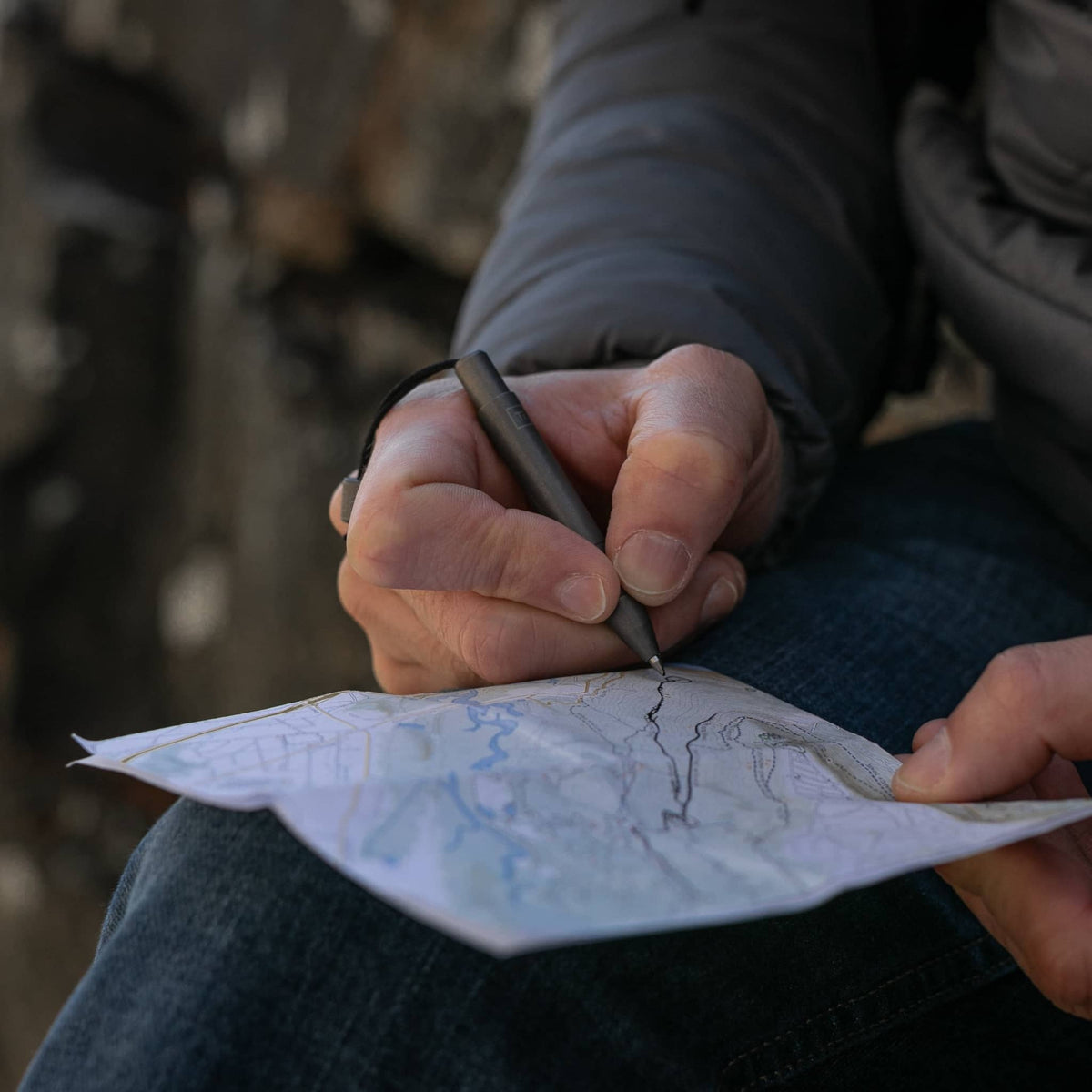 Person using an EDC titanium mini pen from Big Idea Design LLC to mark a map outdoors