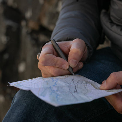 Person using an EDC titanium mini pen from Big Idea Design LLC to mark a map outdoors