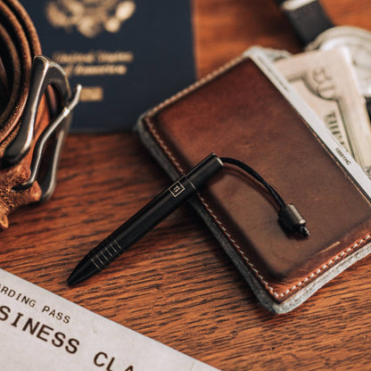 EDC titanium mini pen by Big Idea Design LLC placed on a leather wallet with travel essentials