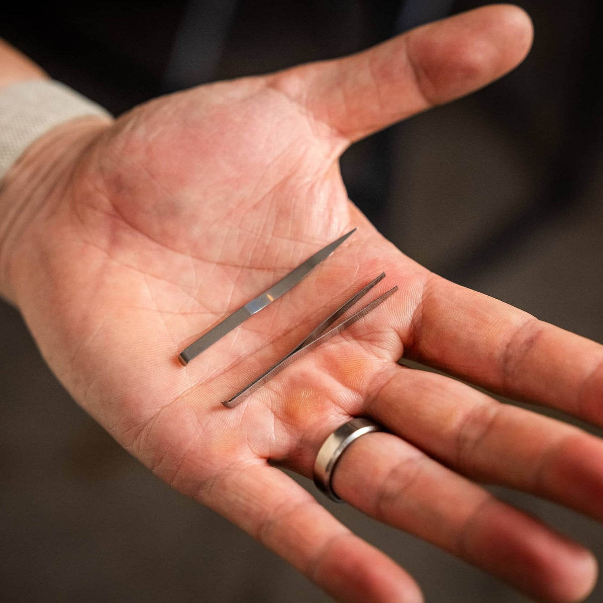 Knafs multi tool pen showing stainless steel tweezers in a hand for precise tasks