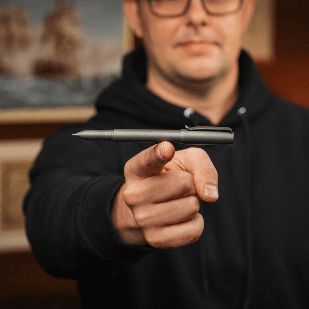 Person holding a sleek titanium capped pen from BIG IDEA DESIGN LLC with a black matte finish