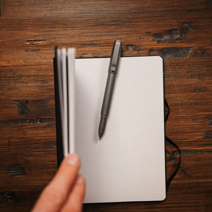 Titanium capped pen placed on an open notebook with a wooden desk background by BIG IDEA DESIGN LLC